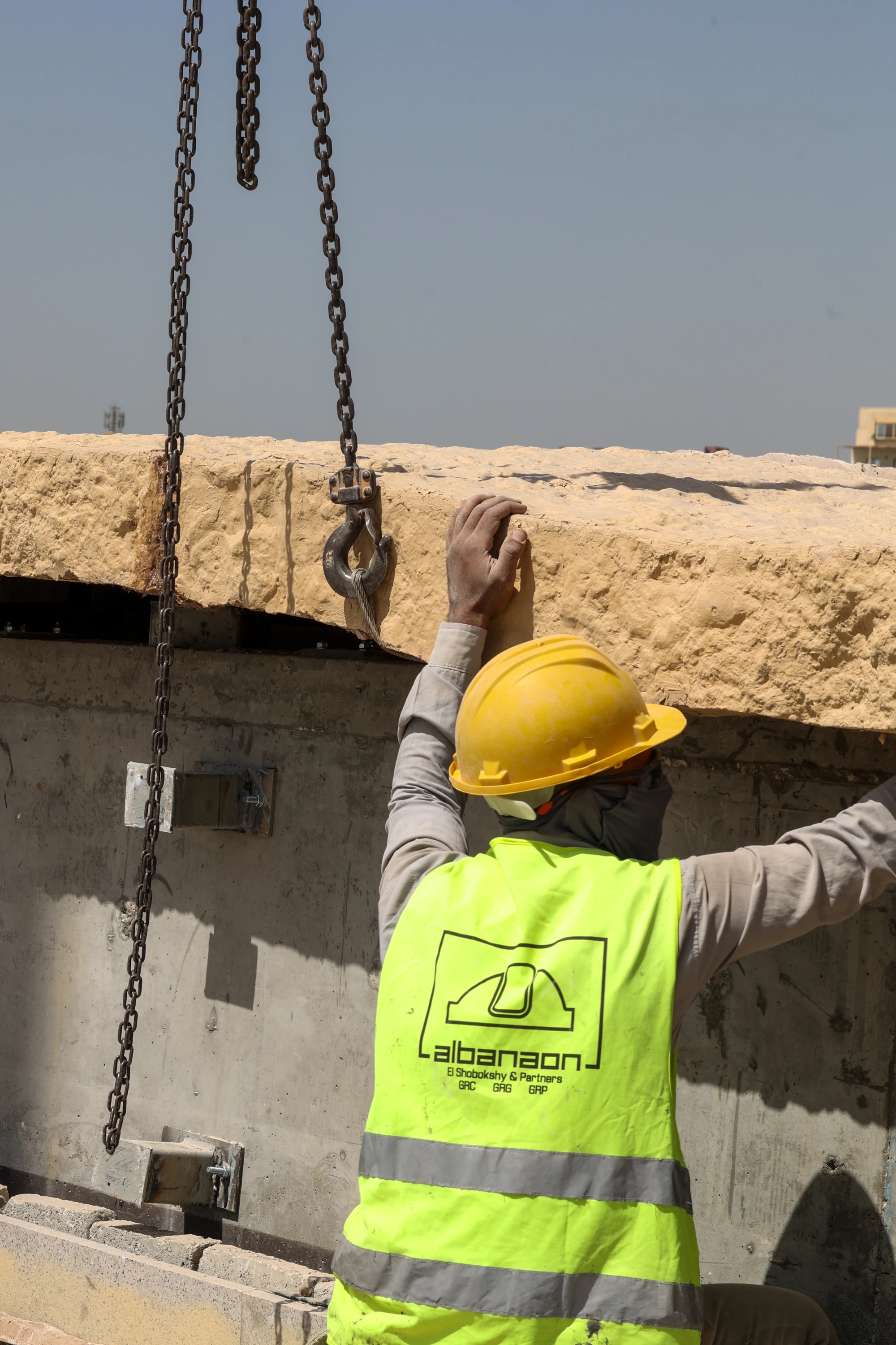 Al Banaon site specialist guiding a suspended architectural element during installation