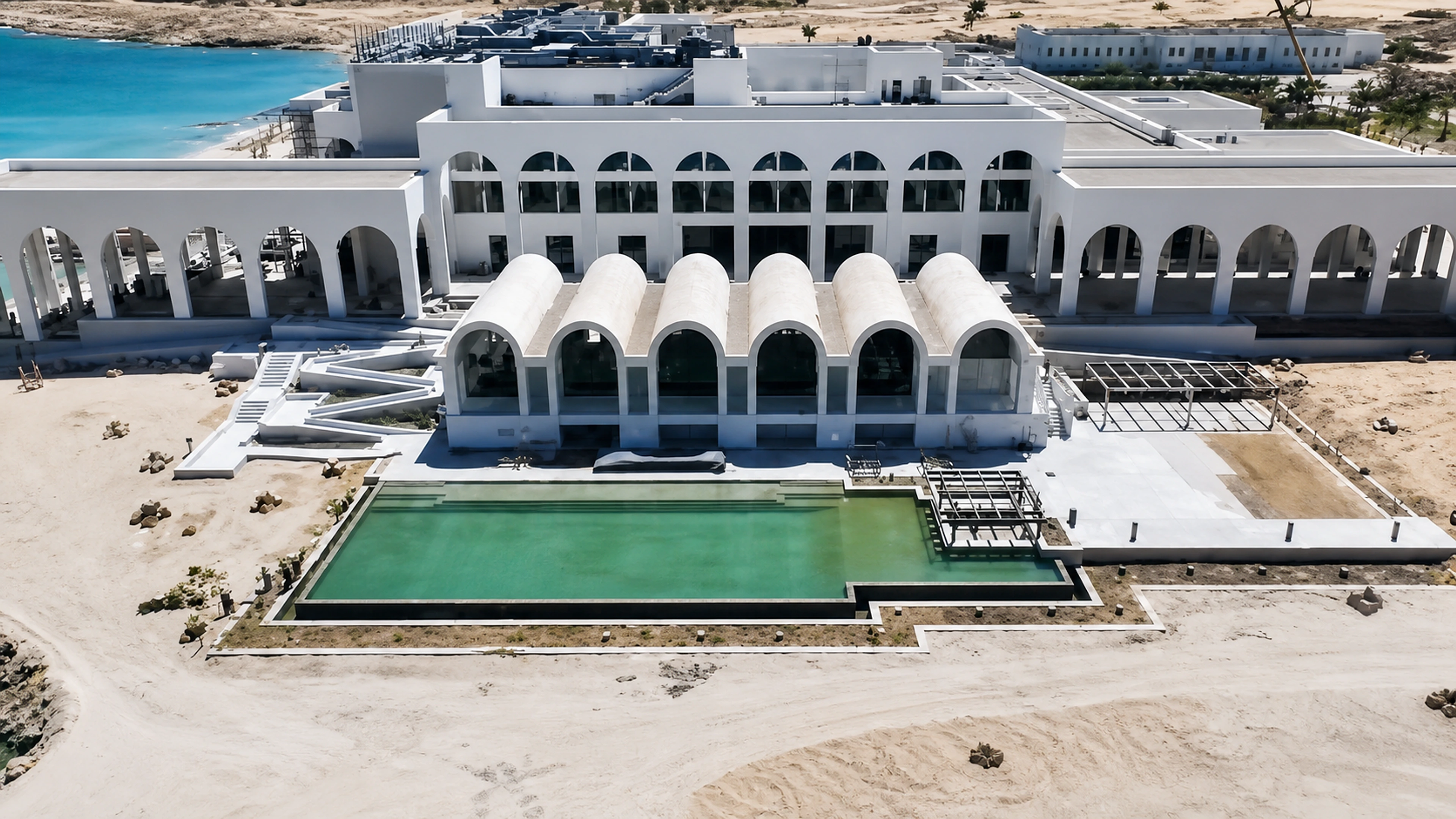 Aerial view of the arched waterfront architecture at Porta Luna in Ras El Hekma